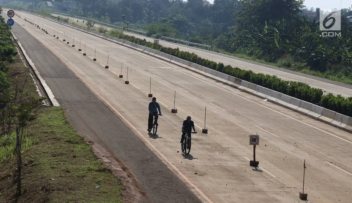 Warga bersepeda di proyek Jalan Tol Cijago Seksi II, kawasan Kukusan, Depok, Minggu (6/1). Proyek yang hampir rampung itu dimanfaatkan untuk berolahraga dengan menyusuri jalur yang belum dilalui kendaraan bermotor. (Liputan6.com/Immanuel Antonius)