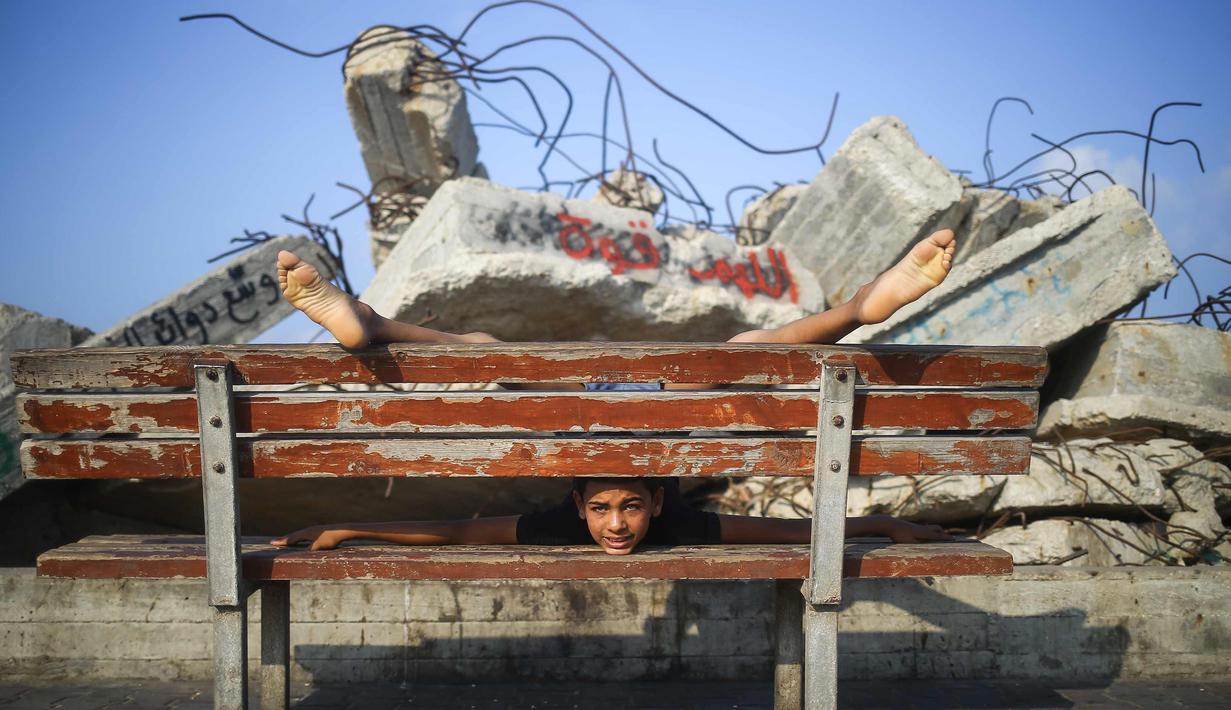 Bocah dua belas tahun Yousef Al-Bahtini melakukan keahliannya di atas bangku di pelabuhan Kota Gaza (20/9). Al-Bahtini saat ini tengah menunggu izin untuk melakukan perjalanan ke Yordania di mana dia akan menunjukkan aksinya. (AFP Photo/Mohammed Abed)