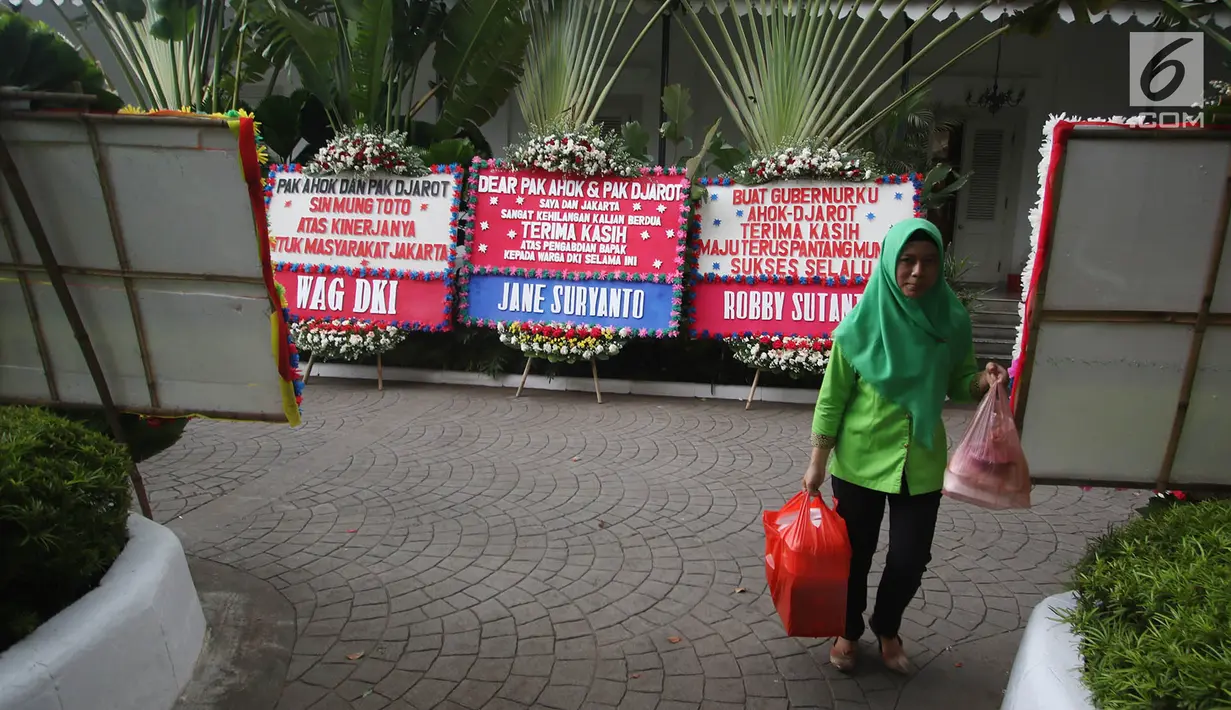 Seorang wanita melintas diantara karangan bunga untuk Ahok dan Djarot yang berada di Gedung Balai Kota, Jakarta, Senin (9/10). Pengirim karangan bunga tersebut beragam, mulai dari pribadi hingga komunitas masyarakat. (Liputan6.com/Immanuel Antonius)