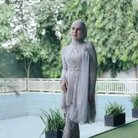 Hijab lilit juga dikenakan Irish Bella saat mengenakan kebaya kurung asimetris abu-abu. Aksen selendang di bahu kiri bikin tambah elegan [@_irishbella_]