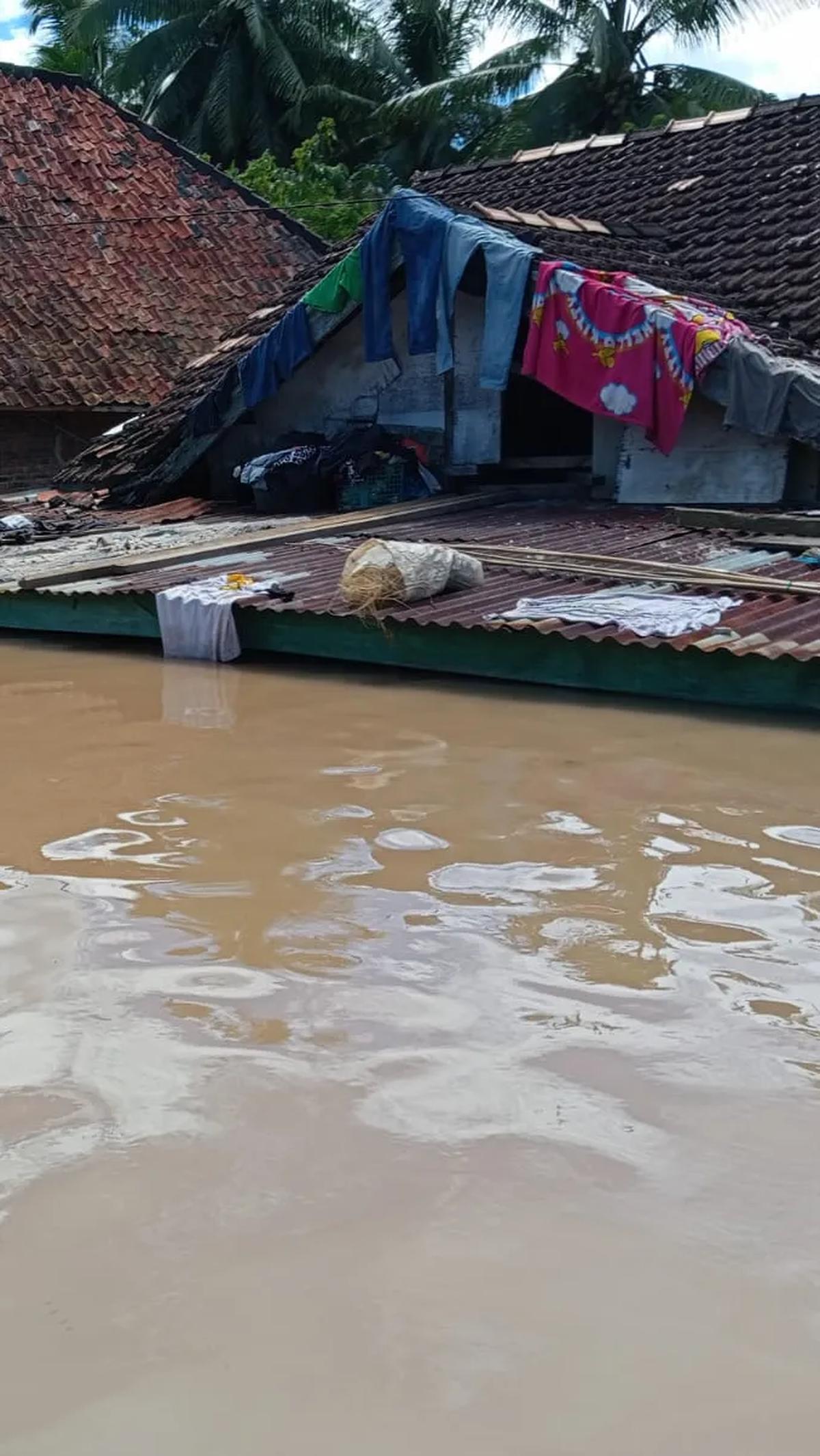 Korban banjir memanfaatkan atap rumah untuk menjemur pakaian