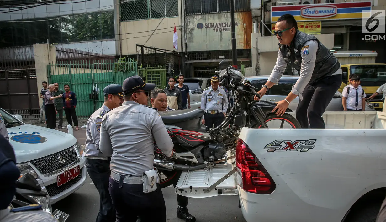 Petugas Dishub mengangkut sepeda motor ke atas truk selama penertiban parkir liar di trotoar kawasan KH Wahid Hasyim, Jakarta, Selasa (1/8). Penertiban dalam rangka Bulan Patuh Trotoar itu untuk mengembalikan fungsi trotoar. (Liputan6.com/Faizal Fanani)