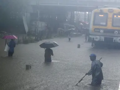 Warga melintasi rel kereta api yang terendam banjir saat hujan lebat di Mumbai, India, Rabu (9/6/2021). Mumbai terendam banjir usai diguyur hujan lebat. (AP Photo/Rafiq Maqbool)