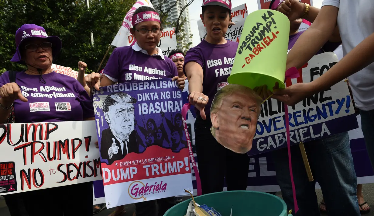 Aktivis membuang foto Presiden terpilih AS, Donald Trump ke dalam tong sampah di depan kedutaan AS, Manila, Filipina (20/1). Dunia akan menyaksikan pelantikan Donald Trump dan Mike Pence sebagai Presiden dan Wakil Presiden AS. (AFP Photo/Ted Aljibe)