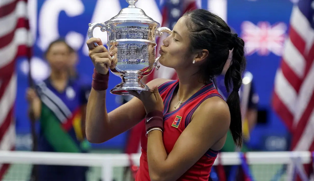 Petenis Inggris, Emma Raducanu mencium trofi usai mengalahkan Leylah Fernandez dari Kanada pada final US Open 2021 di New York, Minggu (12/9/2021). Raducanu mencatatkan diri sebagai wanita Inggris pertama memenangkan grand slam sejak Virginia Wade menjuarai Wimbledon  1977. (AP Photo/Seth Wenig)