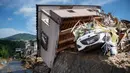 Sebuah mobil tertimpa rumah yang rusak usai banjir melanda Kumano, Prefektur Hiroshima, Jepang, Senin (9/7). Sebanyak 75 orang tewas dalam bencana tersebut. (Martin BUREAU/AFP)