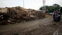 Warga saat melintas di dekat gunungan sampah di Pasar Induk Kramat Jati, Jakarta, Kamis (8/1/2015). (Liputan6.com/Faizal Fanani)