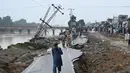Seorang pria melintas di jalan yang rusak akibat gempa bumi melanda pinggiran Kota Mirpur, Pakistan, Rabu (25/9/2019). Gempa bermagnitudo 5,8 menyebabkan kerusakan meluas di jalan-jalan dan bangunan di distrik Mirpur. (Photo by AAMIR QURESHI / AFP)