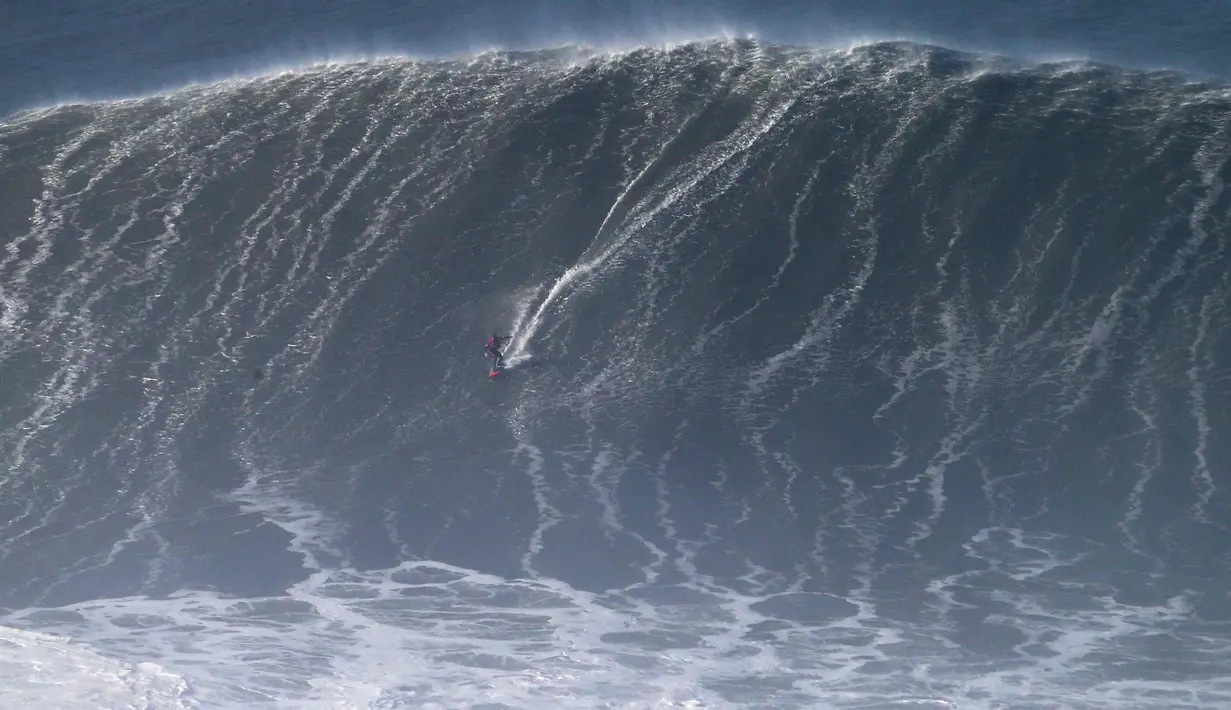 Peselancar asal Portugal, Joao Guedes beraksi saat menaklukan ombak selama sesi surfing ombak besar di Praia do Norte di Nazare, Portugal tengah (13/1). (AP Photo / Armando Franca)