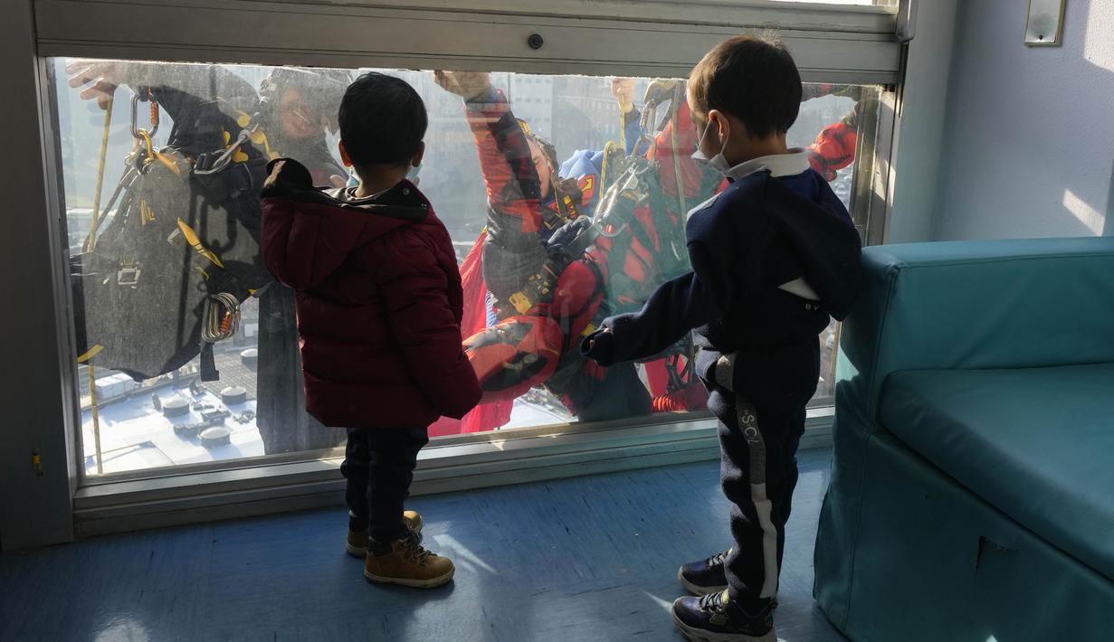 Dua orang berpakaian superhero turun dari atap untuk memberi kejutan di jendela kamar pasien anak di bangsal Pediatri rumah sakit San Paolo di Milan, Italia, Rabu (15/12/2021). Aksi Spiderman dan kawan-kawannya itu untuk menghibur anak-anak yang dirawat di rumah sakit tersebut. (AP Photo/Luca Bruno)