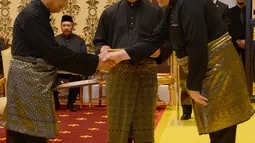 Perdana Menteri Malaysia baru, Mahathir Mohamad (kiri) bersalaman dengan Raja Malaysia Muhammad V saat prosesi sumpah jabatan di Istana Nasional di Kuala Lumpur (10/5). (AFP Photo/ Istana Nasional Malaysia)