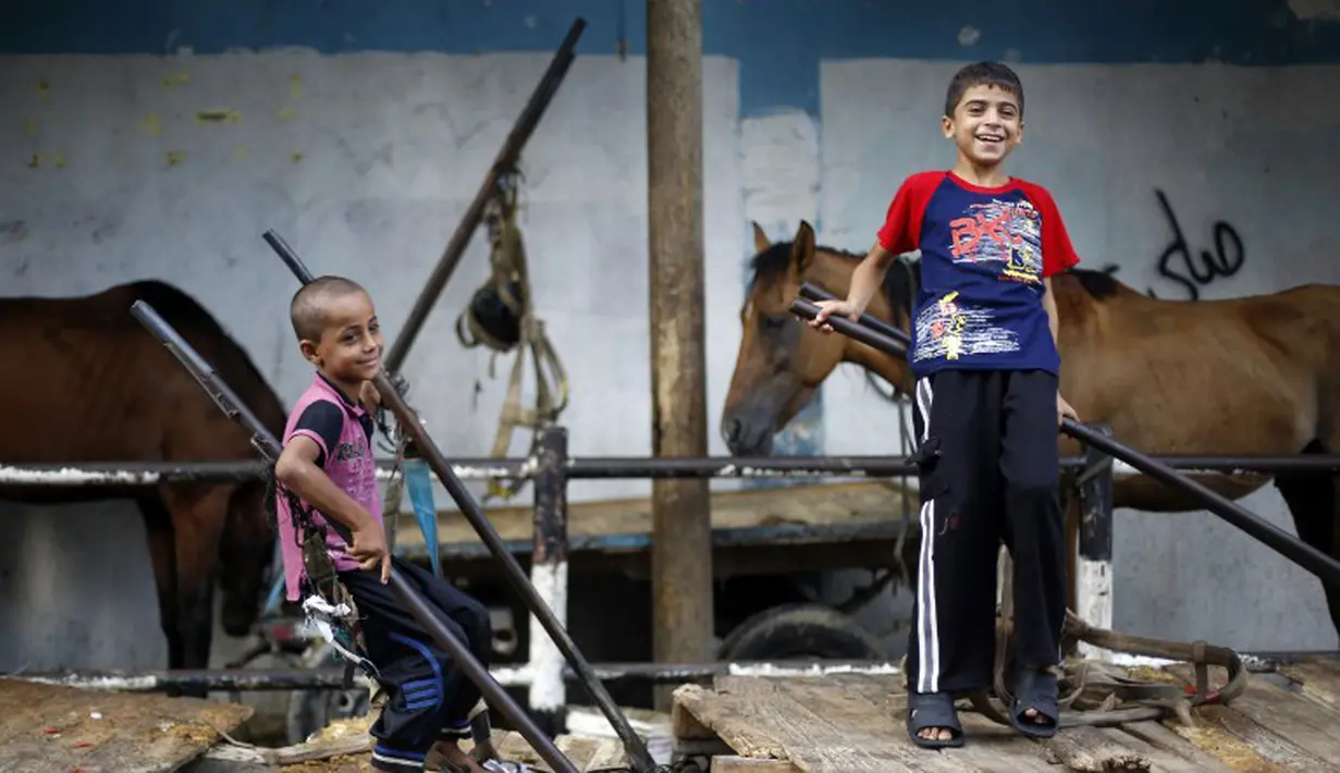 Anak laki-laki Palestina bermain dekat gerobak di kamp pengungsi Sekolah PBB di Jabalia, Gaza (28/7/14). (AFP PHOTO/MOHAMMED ABED )