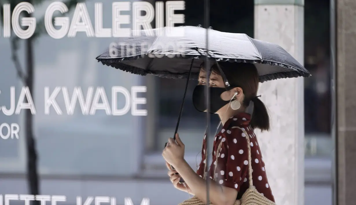 Seorang wanita mengenakan masker untuk mencegah penyebaran Covid-19 terlihat dicermin sebuah toko di Tokyo (12/8/2020). Menurut Badan Meteorologi Jepang, cuaca panas telah ditetapkan dengan suhu naik lebih dari 34 derajat Celcius (93,2 derajat Fahrenheit) di Tokyo. (AP Photo/Eugene Hoshiko)