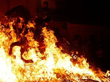 Seorang pria menunggangi kuda melewati api unggun saat festival Luminarias di San Bartolome de Pinares, Spanyol, Jumat (16/1/2020). Festival tersebut digelar setiap tahunnya, sehari sebelum perayaan Santo Antonius yang merupakan pelindung binatang. (AP Photo/Manu Fernandez)
