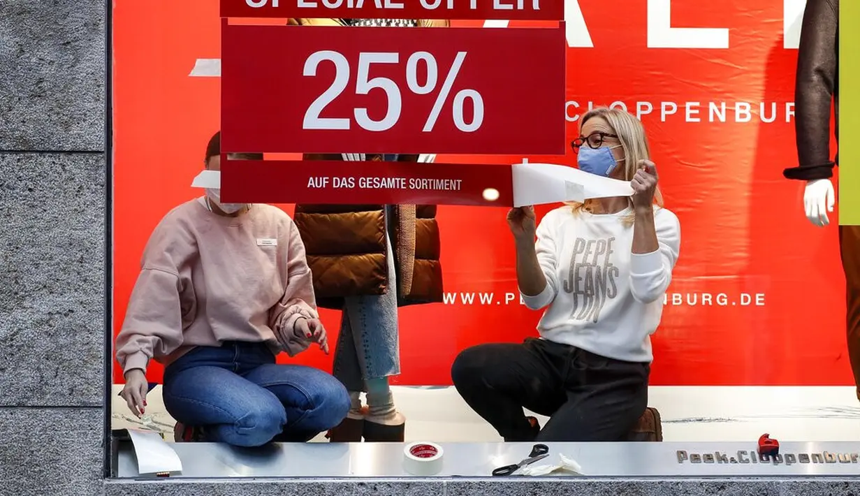 Pekerja memasang iklan penawaran khusus untuk dua hari ke depan di jendela toko di pusat Kota Essen, Jerman, Senin (14/12/2020). Jerman melakukan lockdown nasional pada 16 Desember 2020 untuk memerangi pandemi COVID-19. (AP Photo/Martin Meissner)