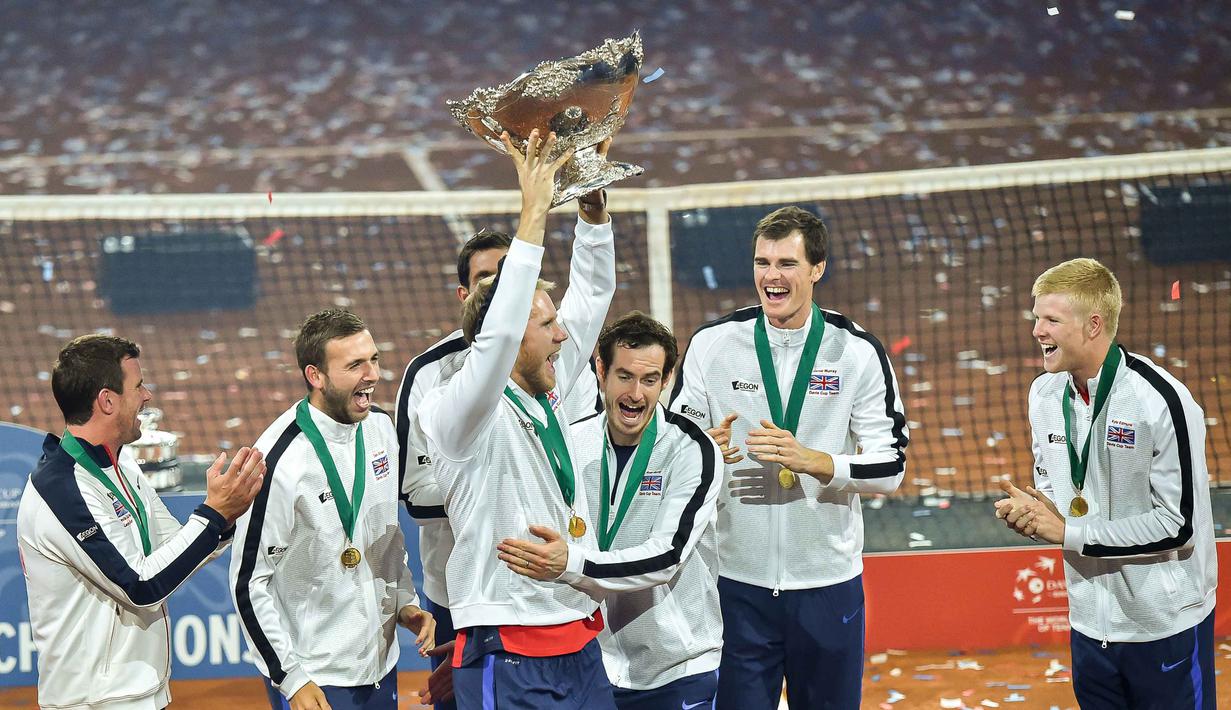 (dari kiri) Petenis Inggris Raya, Leon Smith, Daniel Evans,James Ward,Andy Murray,Jamie Murray, Kyle Edmund tertawa bersama saat Dominic Inglot mengangkat trofi Piala Davis di Flanders Expo, Ghent, Belgia, Minggu (30/11/2015). (AFP Photo/Philippe Huguen)