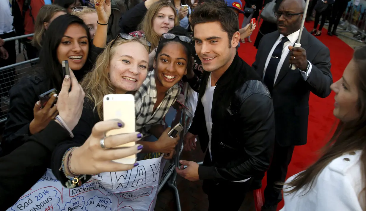 Aktor Zac Efron berfoto selfie dengan para penggemarnya saat menghadiri pemutaran perdana film 'We Are Your Friends' di Brixton Oval, London, Inggris. Selasa (11/8/2015). (REUTERS/Luke MacGregor)