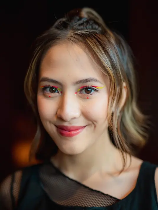 Ingin tampil dengan makeup playful? Permainan grafis eyeliner neon pink dan kuning bisa dicoba. [@zaraadhsty]
