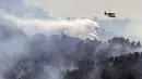 Pesawat pemadam kebakaran menjatuhkan air ke atas kebakaran hutan di dekat Betxi, sekitar 60 kilometer utara Valencia, Spanyol, Senin, 27 Juli 2026. (AFP/ Jose Jordan)