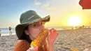 Ingin menikmati keindahan sunset di pantai sambil makan jagung bisa kamu lakukan. Untuk pakaian kamu bisa mrmilih warna cerah yang dipadukan dengan topi sebagai aksesoris