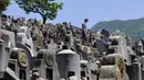 Seorang pria yang mengenakan masker berdiri di makam kerabat saat Festival Ching Ming atau Hari Sapu Makam di Hong Kong, Selasa (5/4/2022). Ribuan warga Hong Kong memberi hormat kepada leluhur dan kerabat mereka selama festival tahunan ini. (AP Photo/Vincent Yu)