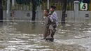 Seorang pria menggendong lansia melintasi  banjir yang merendam Jalan Pondok Raya Gede, Jakarta Timur, Selasa (25/2/2020).  Sejumlah ruas jalan tergenang dan akses ke beberapa wilayah terputus, salah satunya Jalan Pondok Raya Gede. (Liputan6.com/Herman Zakharia)