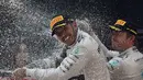Nico Rosberg membalas menyemprotkan sampanye ke muka Lewis Hamilton