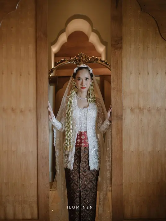 Di pernikahan ke-2 nya, BCL mengenakan kebaya kutubaru putih rancangan Didiet Maulana yang dipadukan obi merah dan kain batik coklat sebagai bawahan. Lengkap dengan veil panjang yang indah. [Foto: IG/Iluminen]