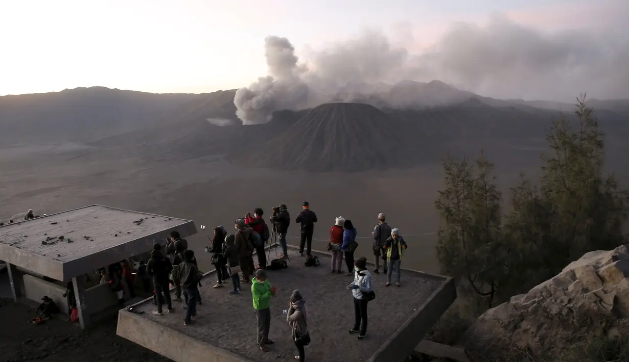 Wisatawan menyaksikan matahari terbit dengan latar belakang Gunung Bromo yang sedang erupsi di Ngadisari, Probolinggo, Jawa Timur, Rabu (6/1/2016). (REUTERS/Darren Whiteside)