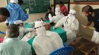 Petugas medis yang mengenakan pakaian pelindung sedang memeriksa pasien di rumah sakit Medical College di Kozhikode, India, pada 21 Mei 2018. (Liputan6/AFP)