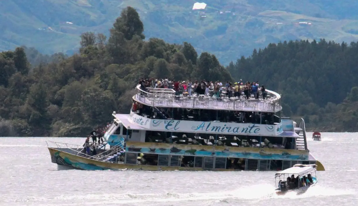 Sebuah kapal mendekati kapal wisata Almirante sesaat sebelum tenggelam di sebuah waduk di Kolombia barat daya, Minggu (25/6). Dilaporkan bahwa kapal yang membawa lebih dari 150 orang itu tenggelam berlangsung kurang dari lima menit. (Juan QUIROZ/AFPP)
