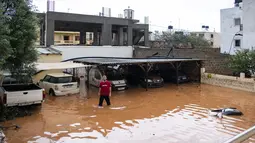 Warga berdiri di area parkir yang terendam banjir setelah hujan lebat di desa Malia, pulau Kreta, Yunani, Selasa (10/11/2020). Banjir besar di Pulau Kreta Yunani merusak jalan, membanjiri ratusan rumah, dan menyeret mobil ke laut di tengah hujan deras yang sedang berlangsung. (AP Photo/Harry Nakos)