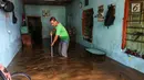 Warga membersihka rumahnya yang terendam banjir di kawasan bantaran kali Cisadane, Tangerang, Jumat (26/4). Banjir kiriman setinggi 2 meter sempat melanda kawasan akibat curah hujan yang tinggi di bogor membuat derasnya air mengalir jauh sampai ke tempat ini. (Liputan6.com/Johan Tallo)