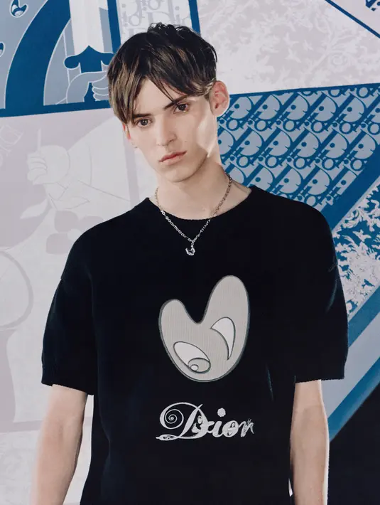 Sementara T-shirt lengan pendek menampilkan logo Dior yang direvisi dengan memadukan wajah yang tersenyum sinis.