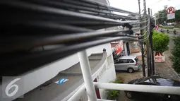 Kabel dari tiang listrik yang melintasi dan menjuntai di JPO kawasan Cawang, Jakarta, Rabu (25/1). Selain mengganggu kenyamanan, buruknya penempatan instalasi kabel tersebut juga berbahaya bagi keselamatan pengguna JPO. (Liputan6.com/Immanuel Antonius)