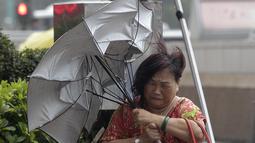 Seorang wanita berusaha melewati angin kencang dari Topan Matmo yang melanda Taiwan, Rabu (23/7/14). (REUTERS/Pichi Chuang)