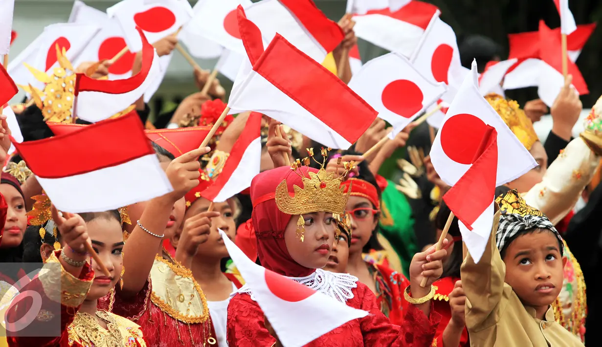 Sejumlah anak mengenakan baju daerah dan membawa bendera Indonesia dan Jepang saat menyambut kedatangan PM Jepang, Shinzo Abe di Istana Kepresidenan Bogor, Jawa Barat, Minggu (15/1). (Liputan6.com/Panca Syurkani/Pool)