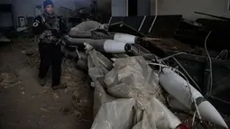 Pasukan khusus Irak berjalan dekat rudal yang ditemukan di sebuah gudang senjata milik ISIS di sisi timur Mosul, Sabtu (28/1). Senjata-senjata yang ditemukan di antara puluhan roket yang tersembunyi di unit penyimpanan di kota. (AP Photo/Khalid Mohammed)
