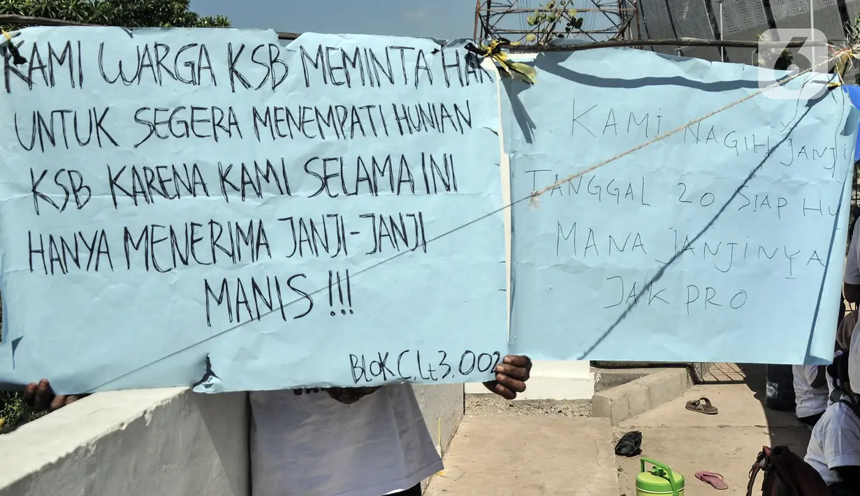 Warga mengangkat poster bertuliskan tuntutan saat berunjuk rasa dengan mendiami tenda pengungsian di depan gerbang Kampung Susun Bayam, Jakarta Utara, Senin (21/11/2022). Berdasarkan kesepakatan, seharusnya warga sudah mulai bisa menempati hunian pada 20 November 2022 kemarin. (merdeka.com/Iqbal S. Nugroho)