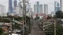 Warga beraktivitas di antara rel kereta dengan latar belakang gedung bertingkat di kawasan Pejompongan, Jakarta, Selasa (5/1/2021). Pemerintah mengalokasikan anggaran untuk PEN 2021 sebesar Rp403,9 triliun, anggaran ini naik dari rencana sebelumnya sebesar Rp372,3 triliun. (Liputan6.com/Johan Tallo)