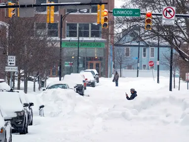 Orang-orang beraktivitas setelah badai salju ekstrem di jalan-jalan Elmwood Village, Buffalo, New York, Amerika Serikat, 26 Desember 2022. Amerika Serikat tengah dilanda badai salju ekstrem. (AP Photo/Craig Ruttle)