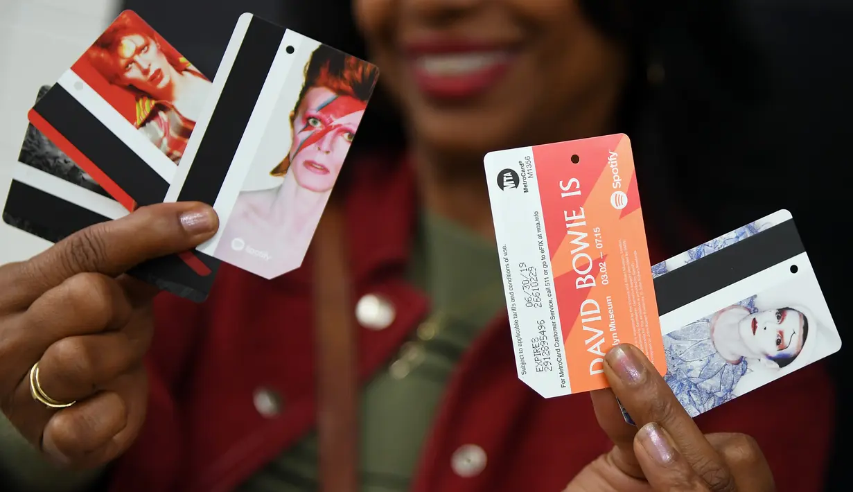 Seorang wanita memegang foto David Bowie yang dijadikan sebagai kartu kereta atau Metro Card di stasiun kereta bawah tanah Broadway-Lafayette, New York City, 19 April 2018. (ANGELA WEISS/AFP)