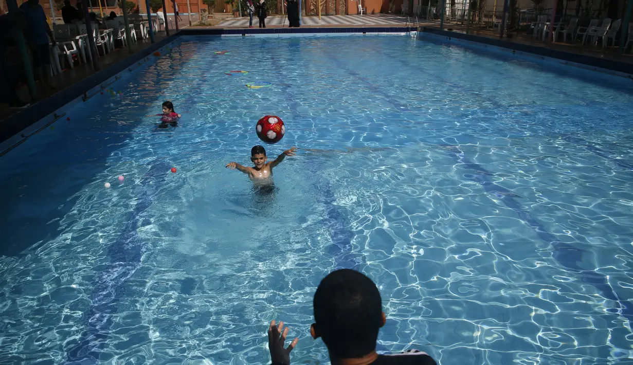 Seorang anak laki-laki Palestina yang menderita autisme melempar bola saat berpartisipasi dalam sesi terapi renang di Beit Lahia di Jalur Gaza utara  (5/8/2019). (AFP Photo/Mohammed Abed)