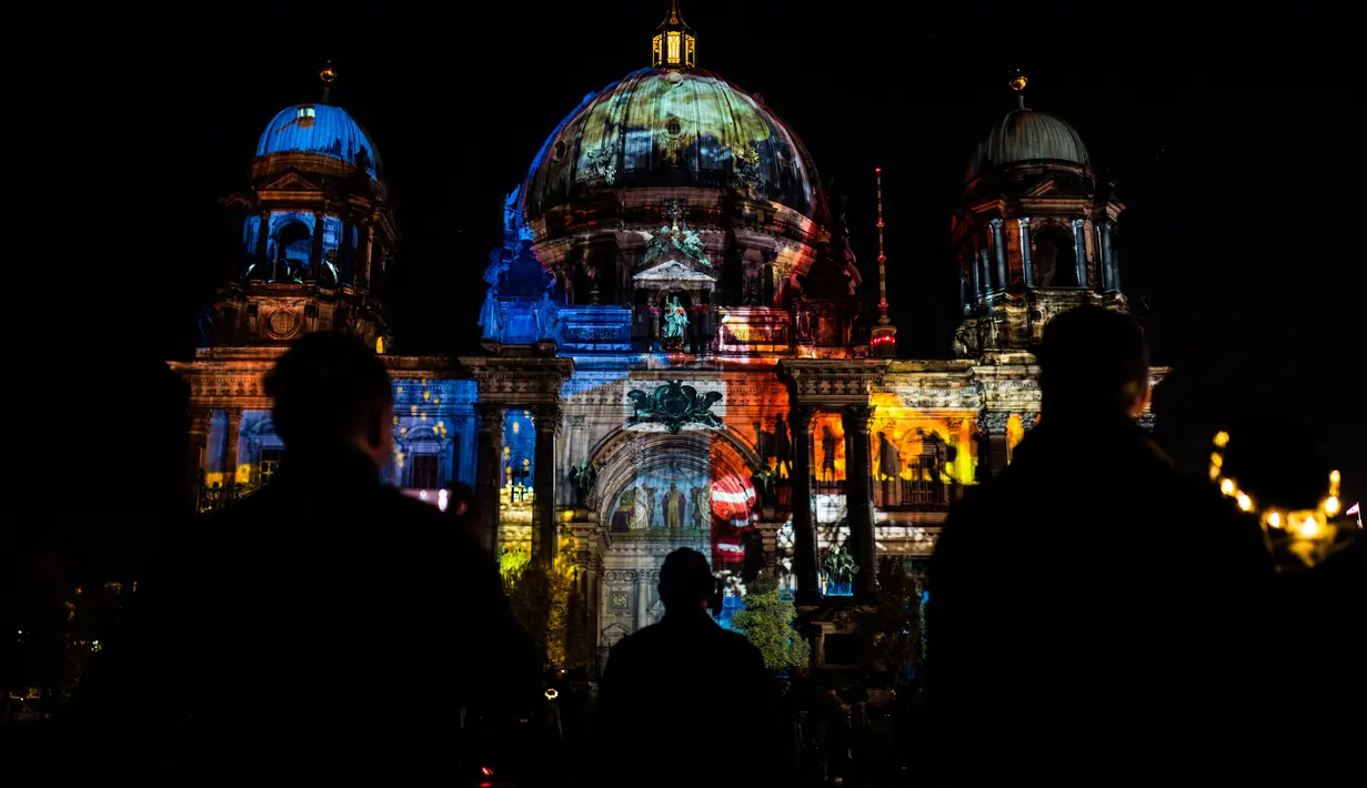 Sejumlah wisatawan menikmati bangunan Katedral Berlin yang dihiasi cahaya saat Festival Cahaya di Berlin, Jerman (15/10). Festival ini merupakan event tahunan yang diadakan setiap bulan Oktober. (AFP Photo/John Macdougall)
