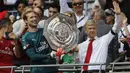 Arsene Wenger (kanan) akhirnya mengangkat trofi juara setelah timnya mengalahkan Chelsea lewat adu penalti 4-1 pada Community Shield 2017  di Wembley Stadium, London, (6/8/2017). (AFP/Frank Augstein)