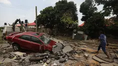 Seorang wanita berjalan melalui jalan yang terkena banjir bandang setelah hujan lebat di Trademoore Estate, Lugbe, Abuja, Nigeria (13/9/2021). Badan Manajemen Darurat Nasional Nigeria (NEMA) mengkonfirmasi 3 orang tewas, dan puluhan mobil dan rumah terkena dampak di malapetaka. (AFP/Kola Sulaimon)