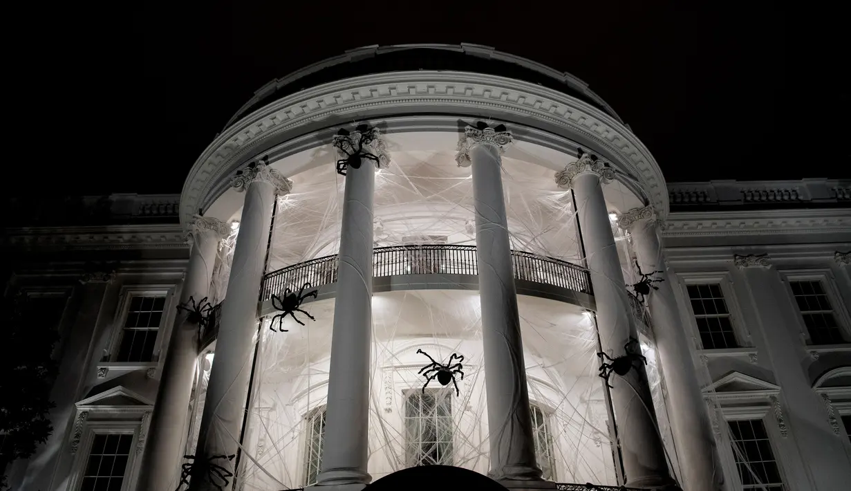 Laba-laba raksasa beserta jaringnya terlihat memenuhi pelataran Gedung Putih, Washington DC, AS, Sabtu (28/10). Laba-laba raksasa tersebut merupakan boneka yang sengaja dipasang dalam rangka menyambut Halloween. (Brendan Smialowski / AFP)