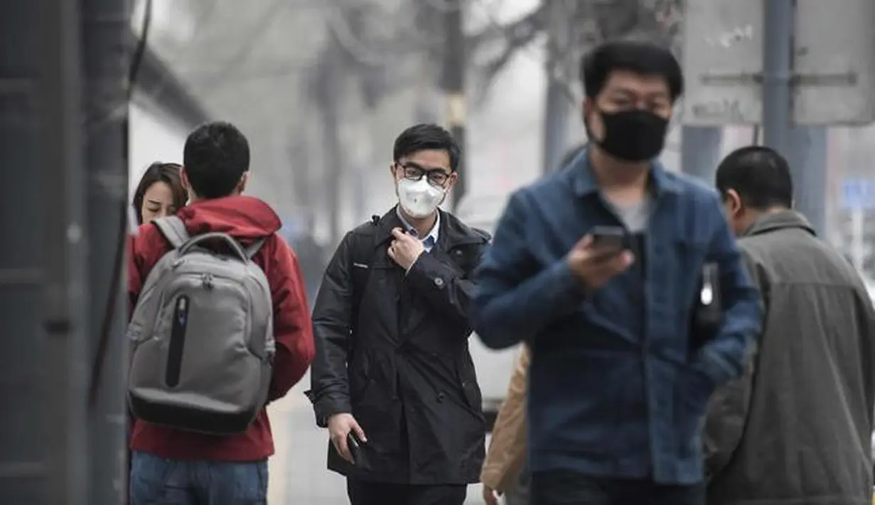 Sejumlah warga mengenakan masker wajah berjalan menyusuri jalan pada hari yang tercemar polusi di Beijing, China (2/4). (AFP Photo/Fred Dufour)