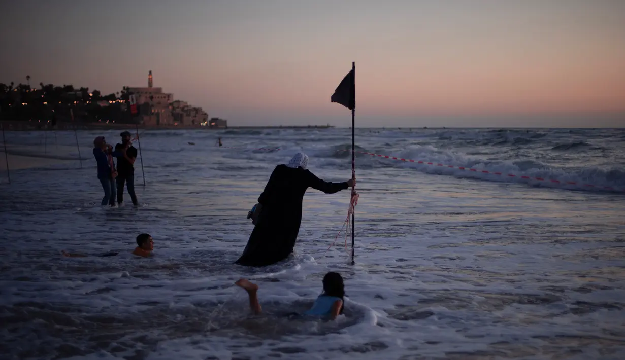 Orang-orang Arab Israel menikmati laut Mediterania selama liburan Idul Fitri, di Tel Aviv, Israel (25/5/2020). Idul Fitri menandai akhir bulan suci Ramadhan, perayaan tiga hari yang biasanya menggembirakan telah berkurang secara signifikan karena pandemi coronavirus.  (AP Photo/Oded Balilty)