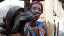 Penjual memperlihatkan sebuah siput yang dijualnya di sebuah pasar di Abidjan, Pantai Gading, Kamis (16/3). Siput menjadi salah satu hewan yang biasa dikonsumsi di daerah tersebut. (AFP PHOTO / ISSOUF Sanogo)